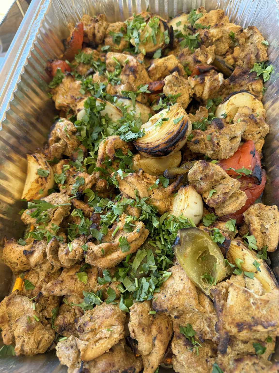 Catering tray of seasoned chicken with vegetables and herbs