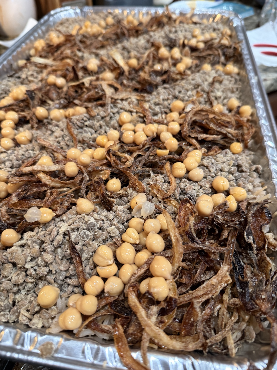 Catering tray of rice topped with nuts and caramelized onions